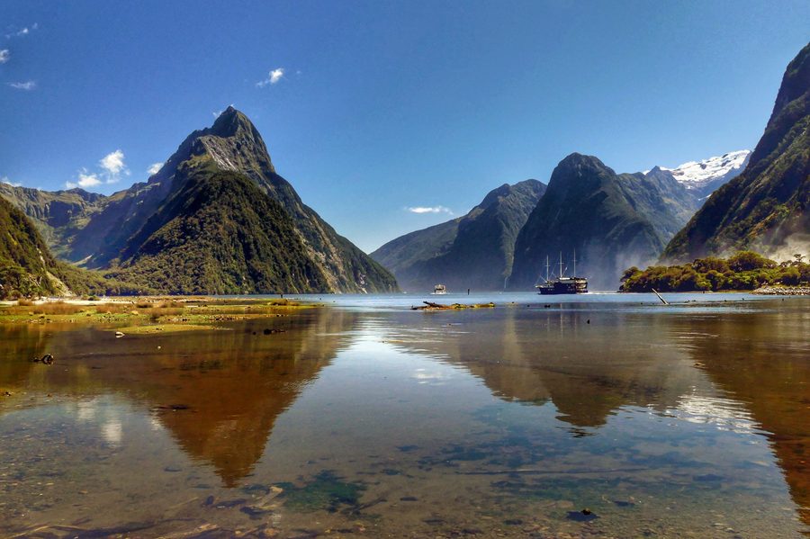 Milford Sound en Nouvelle-Zélande avec des parois rocheuses abruptes sculptées par les glaciers, des cascades et des eaux sombres du fjord