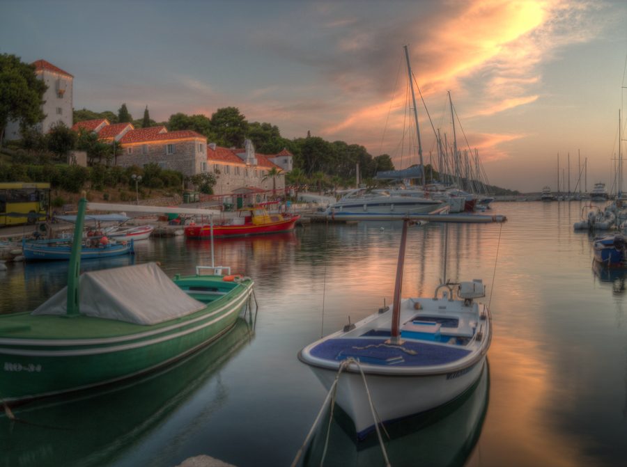 Port de Maslinica sur l'île de Šolta au coucher du soleil avec un bateau de pêche et le paysage côtier